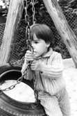 Ett barn som sitter på kanten av en gunga. Holtermanska daghemmet 1973.