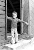 En pojke som står i ingången till ett förrådshus. Holtermanska daghemmet 1973.