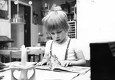 Ett barn som tittar i en bilderbok. Holtermanska daghemmet maj 1975.