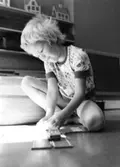 En pojke som leker på golvet med en bilbana. Holtermanska daghemmet, okänt årtal.