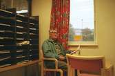 En äldre man som sitter och läser en tidning på biblioteket. Mölndalsbro i dag - ett skolpedagogiskt dokumentationsprojekt på Mölndals museum under oktober 1996. 1996_1227-1245 är gjorda av högstadieelever från Kvarnbyskolan 9D, grupp 6. Se även 1996_0913-0940.