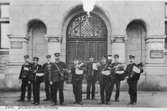 Brevbärarlaget utanför postkontoret i Falun, 1906.  Från vänster till höger:  Johan A. Mårtensson, August Forsström, A.H.M. Kocken, -- , August Nyberg, Lundin, Erik L. Östlund, Bernhard Sandqvist, Verner Söderqvist.