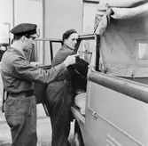 Chaufför Einar Andersson, t.v., får hjälp av montör Eric Carlsson
hos Alenius & Co, med justering av körriktningsvisaren på
Volkwagen-lastbilen. Genom de påfrestande stadskörningarna uppstår
det småskavanker ibland.