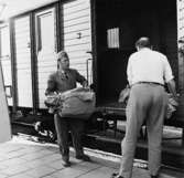 Posten lossas från tåget i Åkersberga. Lantbrevbärare Ingemar
Karlsson och förste postiljon Rolf Håkansson hjälps åt.