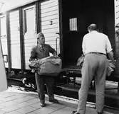 Posten lossas från tåget i Åkersberga. Lantbrevbärare Ingemar
Karlsson och förste postiljon Rolf Håkansson hjälps åt.