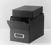 Kortlåda av papp, med löst lock och delvis nedfällbar framsida.
Locket ligger löst ovanpå.