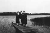 Tre personer står på en brygga vid Tulebosjön i Stretered, 1920-tal.
Från vänster står Linnea Krantz (gift med Carl Krantzs kusin), Carl Krantz (skomakarmästare på Stretered) och Nora Krantz. Carl och Nora Krantz är morföräldrar till givaren.