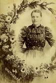 Halvfigursporträtt av en ung kvinna, 1890-tal.
Fotografiet är ett sk visitkort. Dessa blev mycket populära och vanliga från 
och med 1860-talet, då ny teknik gjort det möjligt att framställa flera kopior ur ett negativ. 
Både privatpersoner och 