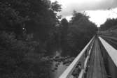 En gångbro av trä över forsen och Grevedämmet, Kvarnfallet 31, Mölndal hösten 1994.