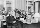 Överdirektör Allan Hultman omgiven av bokgåvor, adresser, blommor
m.m.