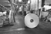 En arbetare med en pappersbal.
Bilden ingår i serie från produktion och interiör på pappersindustrin Papyrus, 1980-tal.