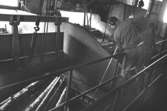 En man i arbete med träråvara, 1980-tal.
Bilden ingår i serie från produktion och interiör på pappersindustrin Papyrus.