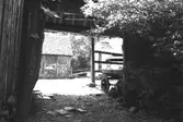 Ett portlider som leder in till en stensatt gårdsplan. Högen 2:1/2:2 i Kållered, 1992-06-30.