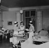 Tre sjuksköterskor delar ut mat på Sabbatsbergs sjukhus i Stockholm, 
cirka 1958. Alltid med nedkavlade ärmar.