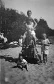 Vuxna och barn leker tillsammans på stranden vid Tulebosjön cirka 1930. Här har de skapat en människo-pyramid.