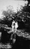 Två badklädda kvinnor står vid strandkanten, troligtvis vid Tulebosjön cirka 1930.