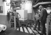 Pallpackning på kartongen, byggnad 6 på pappersbruket Papyrus i Mölndal, år 1990. Mannen med spettet är Gotthard Olsson, mannen i mitten är Tage Carlsson och mannen längst till höger är Arne Larsson. Mannen i bakgrunden är okänd.
