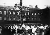 Midsommarfirande vid Streteredshemmet i Kållered, 1930-tal. Stora skolan bakom staketet.