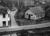 Vy från pappersbruket Papyrus område i Forsåker, Mölndal, mot bebyggelse vid Kvarnbygatan i Mölndals Kvarnby på 1960-talet. Till vänster ses nr 27 som inrymde C.J. Johanssons Järnhandel. Till höger ses nr 29 som var Mölndals första stadshus. En rådstuga som med tiden blev affär för radio och sport.
