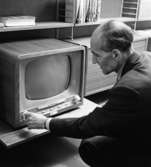 Strinninghylla med tv-apparat
Man som instruerar vid en TV
Inredning
