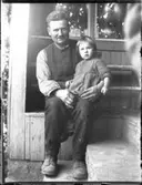 Morbror Oskar i arbetskläder med Inga-Lisa i knät.