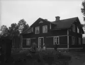 Två män och en kvinna framför ett hus