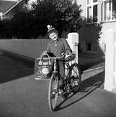 Tom Andersson vid sin cykel med limpsadel. I handen har han sin väska med svenska flaggan, en VM fotboll och några länders namn på.