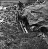 Byggnad N:o 6, tillbyggnad 1954. Läggning av avlopps- och dräneringsrör.
Tre okända män.