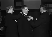 Man får medalj av landshövding Hilding Kjellman, med assistans av kvinna. Uppsala i april 1945
