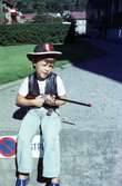 En pojke utklädd till cowboy med leksaksgevär i handen sitter utanför Börefelts Livs i Huskvarna.