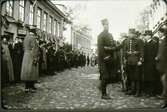 Järnvägsgatan (Rantavägen) med stadshotellet, förut Jouvins hotell t.v. under manövern 1912. Mannen som syns mot den första flaggstången i gatan är bokhållaren Otto Rehn på bryggeriet Victoria.