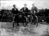 Tre män med cyklar.