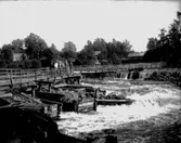 Sex personer på en träbro.
Bostadshus.