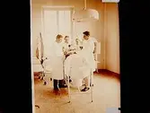 Regemente, Grenadjärer, I3.
Sjukhuset, interiör av operationssalen, tre män och en kvinna.
Furir Almberg