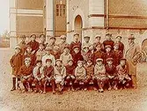 Norra Folkskolan, 31 skolpojkar med lärare. Skolbyggnad i bakgrunden.
N. Bäck