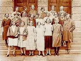 Norra Folkskolan, Högre Folkskolan eller Fortsättningsskolan, 20 skolflickor med lärare. Skolbyggnad i bakgrunden.
N. Bäck