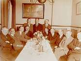 Rumsinteriör, grupp 12 herrar vid bordet.
David E. Flodin