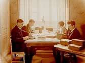 Blå Bandets expedition, 4 personer vid ett skrivbord.