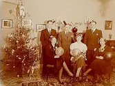Rumsinteriör, familjegrupp 6 personer och julgran.
Nyårsafton den 31 december kl.11.00.
Köpman Carl Eklöf