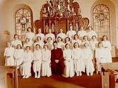 Konfirmander, 26 flickor och pastor Gösta Svensson.Interiör av Viby kyrka.