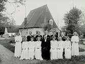Kvistbro kyrka med klockstapel.
Konfirmander, 8 flickor, 5 pojkar och kyrkoherde Thorell.