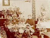 Rumsinteriör, en kvinna.Fruns 50 årsdag.Packmästare Erik Em. Lindh