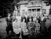 Tvåvånings bostadshus med balkong, veranda, förstuga och frontespis.
Familjegrupp 13 personer framför huset.
Gustaf Petterssons 60 årsdag.
Lindbacka gård, Ånsta socken.