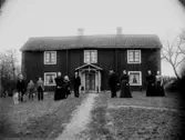 Tvåvånings bostadshus, grupp 10 personer framför huset.
Carl G. Carlsson