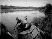 Två flickor i en roddbåt plockar näckrosor i Marksjön.
Märta och Ingrid Lindskog.
