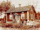 Bostadshus, grupp 6 personer framför huset.Edv. Andersson