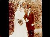 Brudpar, bruden i vit klänning, slöja och krona, brudgummen i frack och hög hatt.
Emil Gustafsson