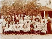 Glashyttans skola, 36 skolbarn med lärarinna fröken Gunnarsson.
Tvåvånings skolbyggnad i bakgrunden.