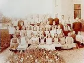Almby skola, 38 skolbarn med lärare.
Skolbyggnad i bakgrunden.
Magister Lundells klass, Almby.