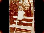 En liten flicka på trädgårdssoffan.
Josef Larsson
